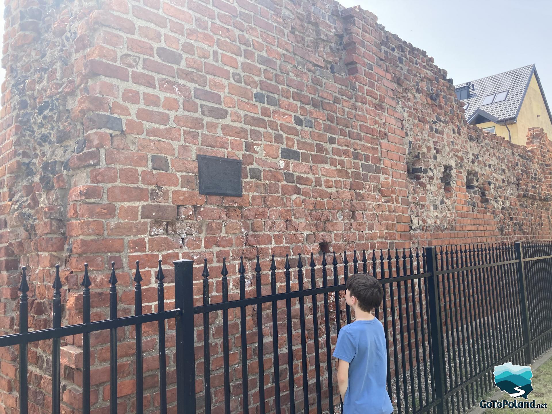 a boy standing by the preserved fragment of the medieval defensive wall