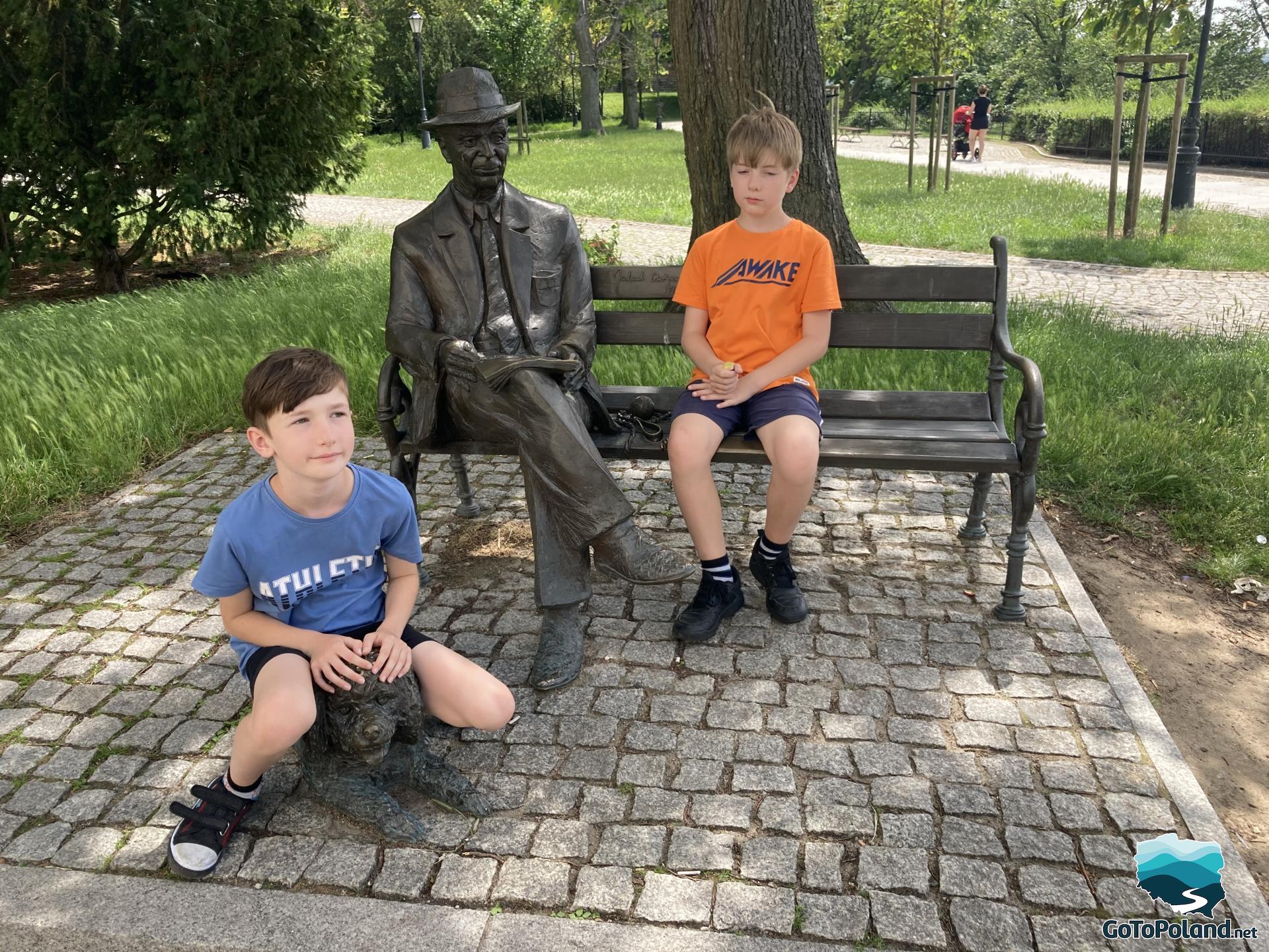 Two boys by the sculpture of a man