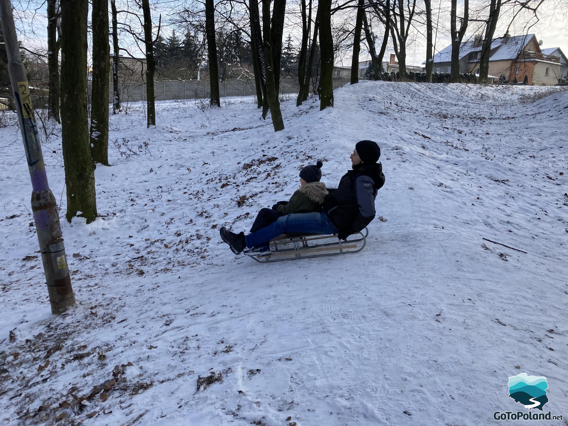 A young boy and his father sledding together