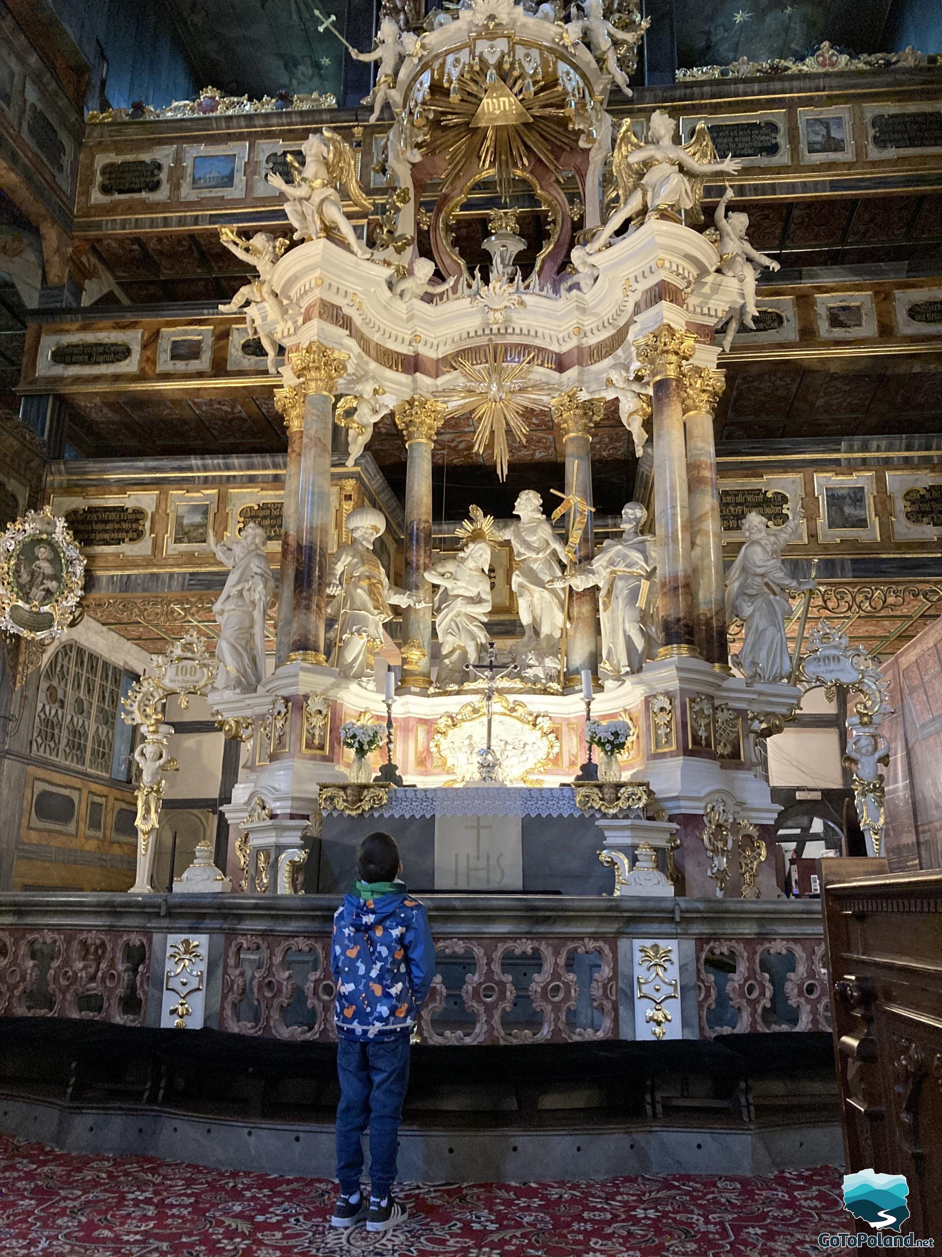 A boy is looking at the main altar. This altar was made of wood