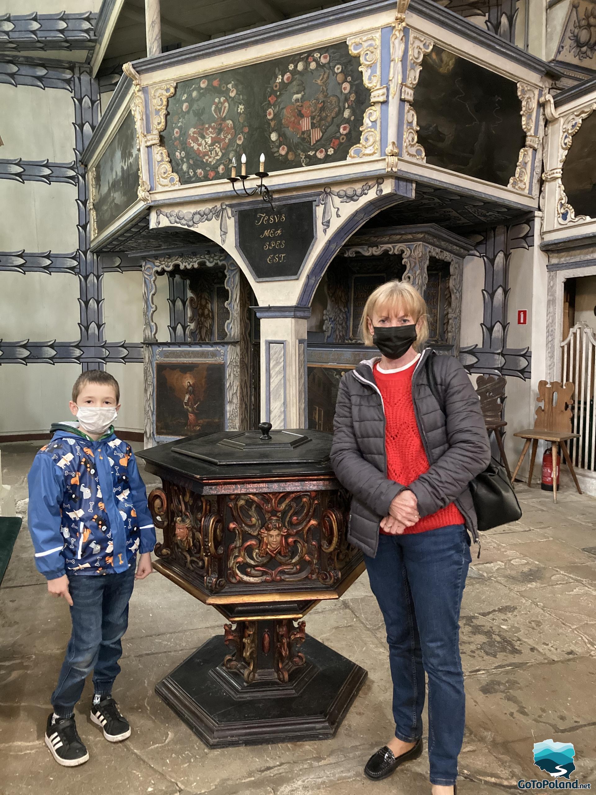 a woman and a boy standing by the historic baptismal font