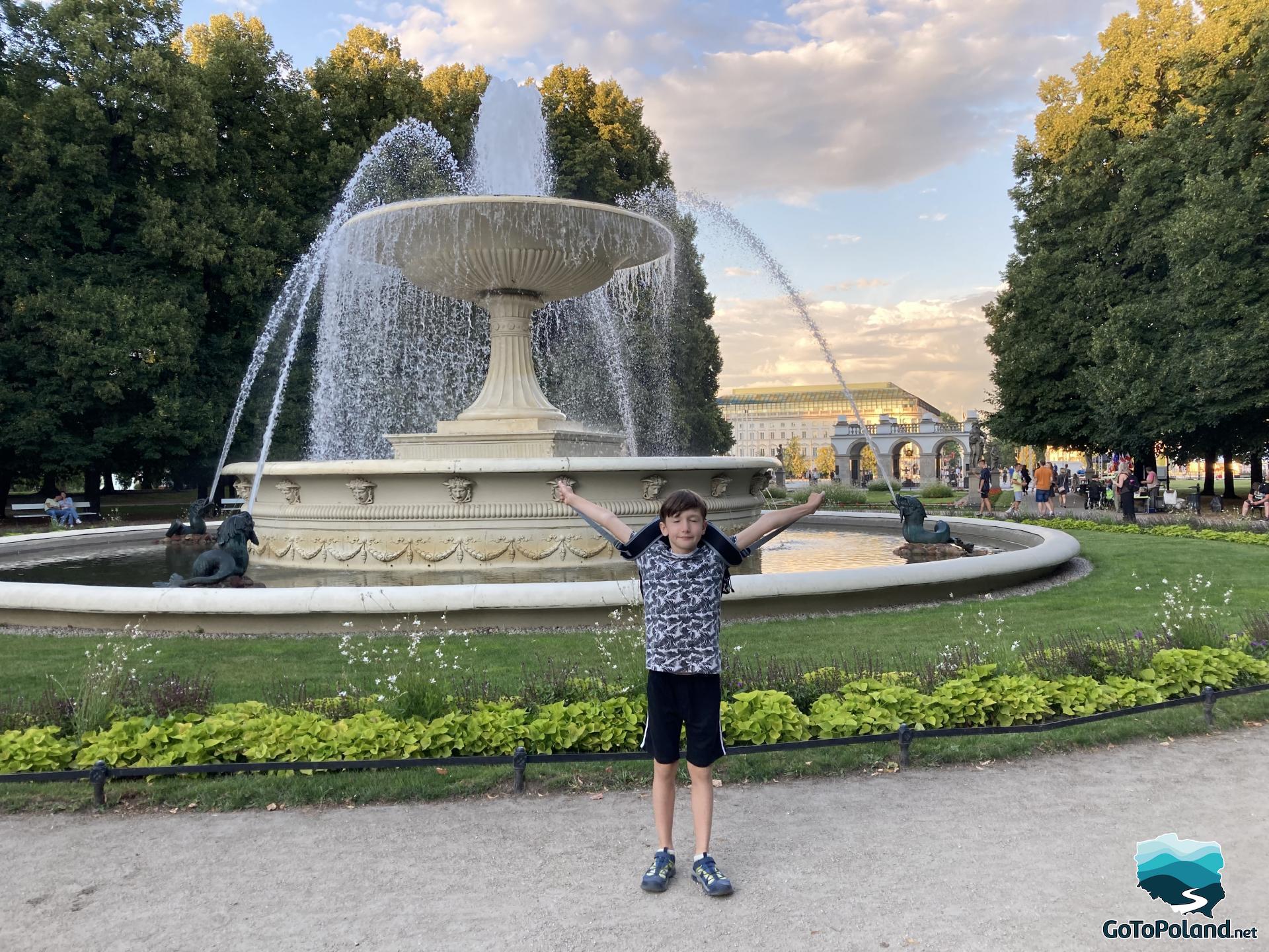 a little boy is standing in front of a round fountain