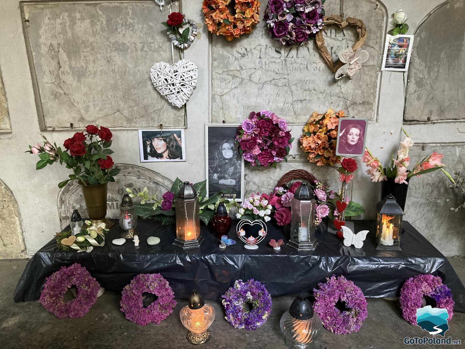 a wall with photos commemorating the dead singer, there are also flowers and artificial hearts