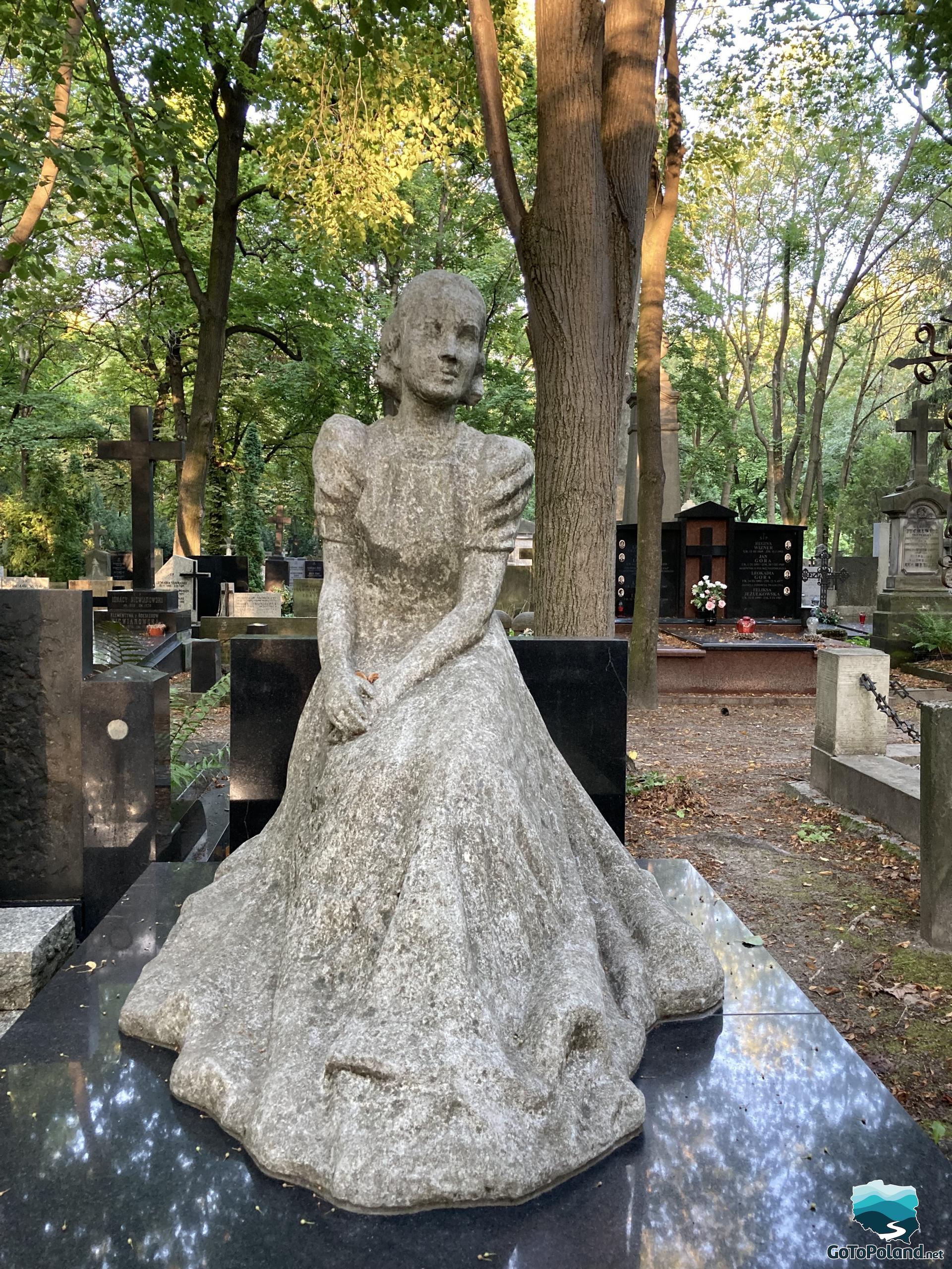 a stone statue presenting a woman, standing in the cemetry