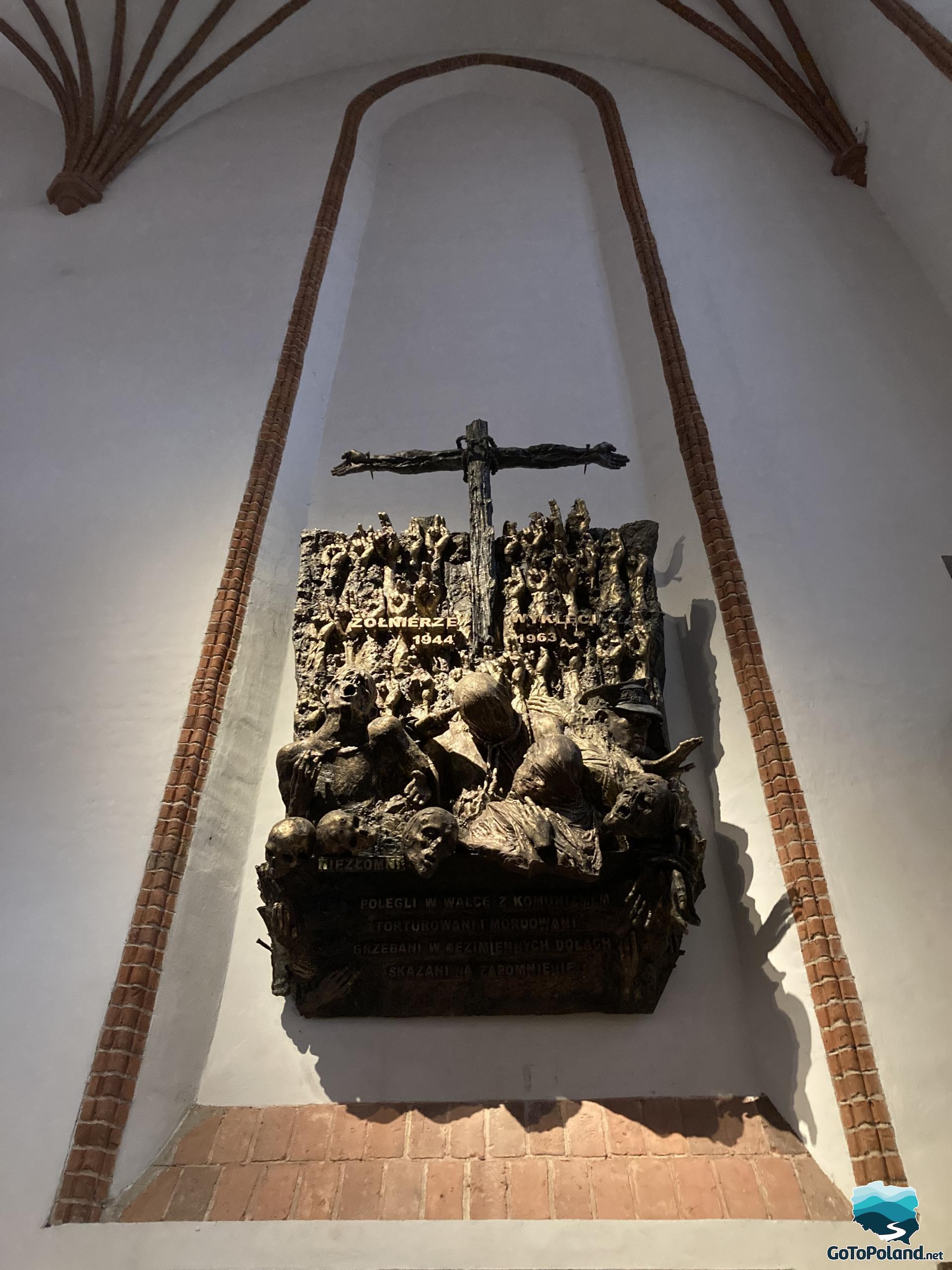 a bronze figure of people raising their hands to the cross