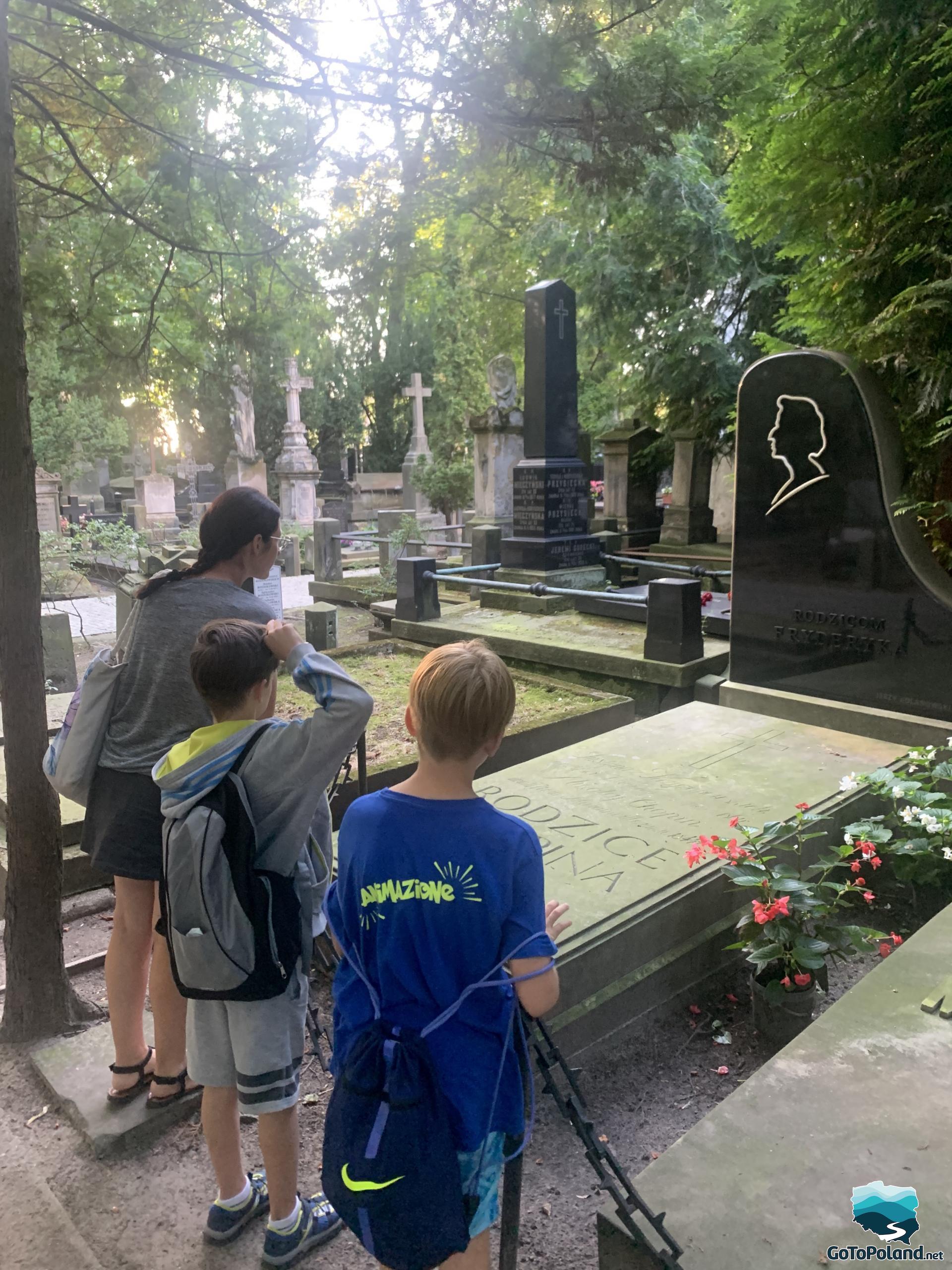 A woman and two boys are standing in front of the grave of Chopin's parents