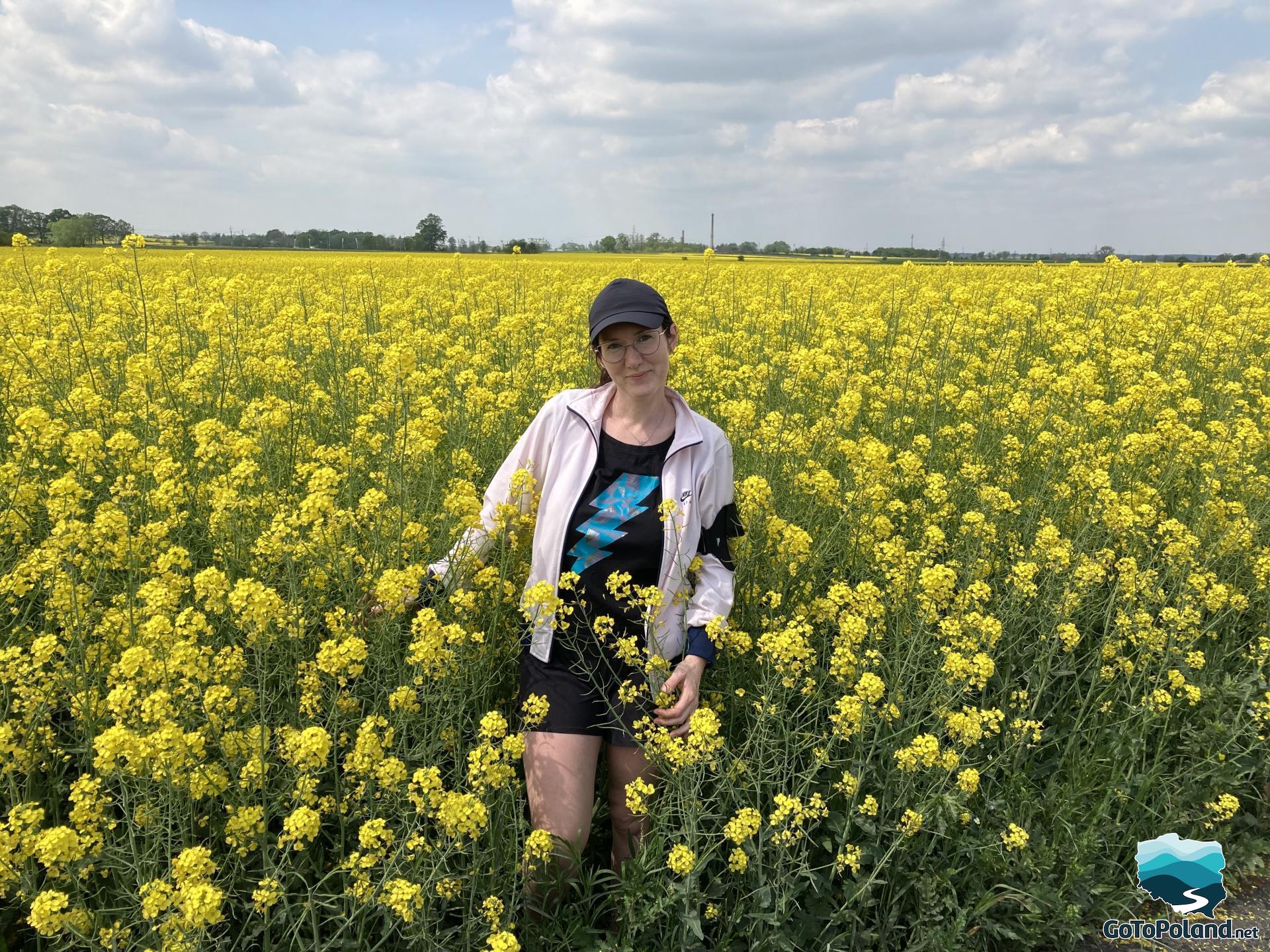 A woman standing between the yellow flowers