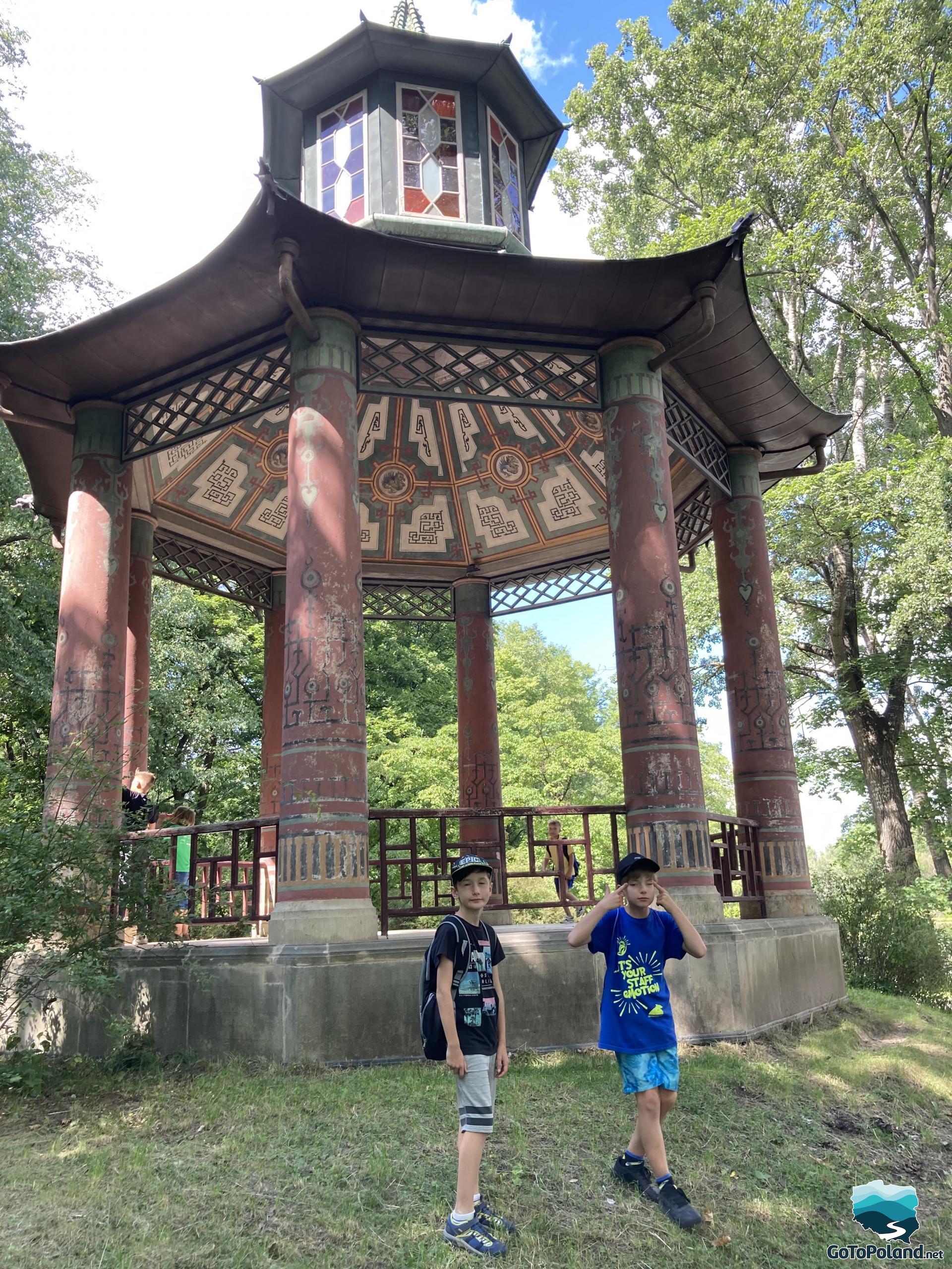 two boys are standing next to Chinese style pavilion  