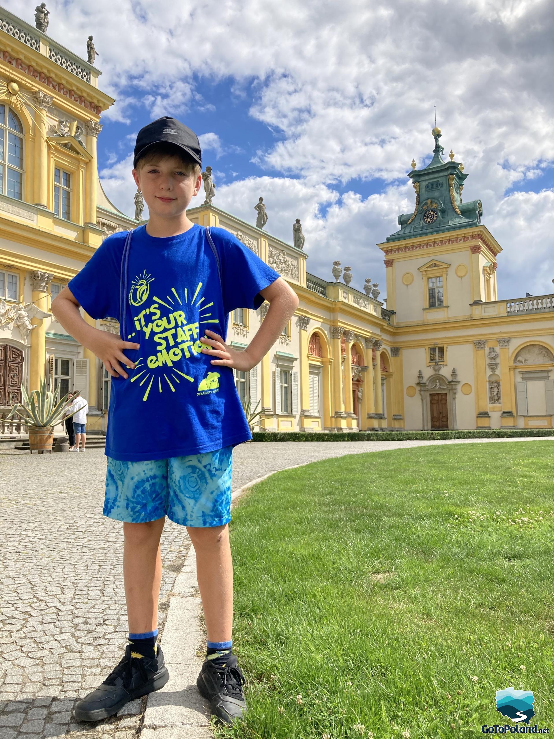 a boy is standing in front of a palace with a yellow facade
