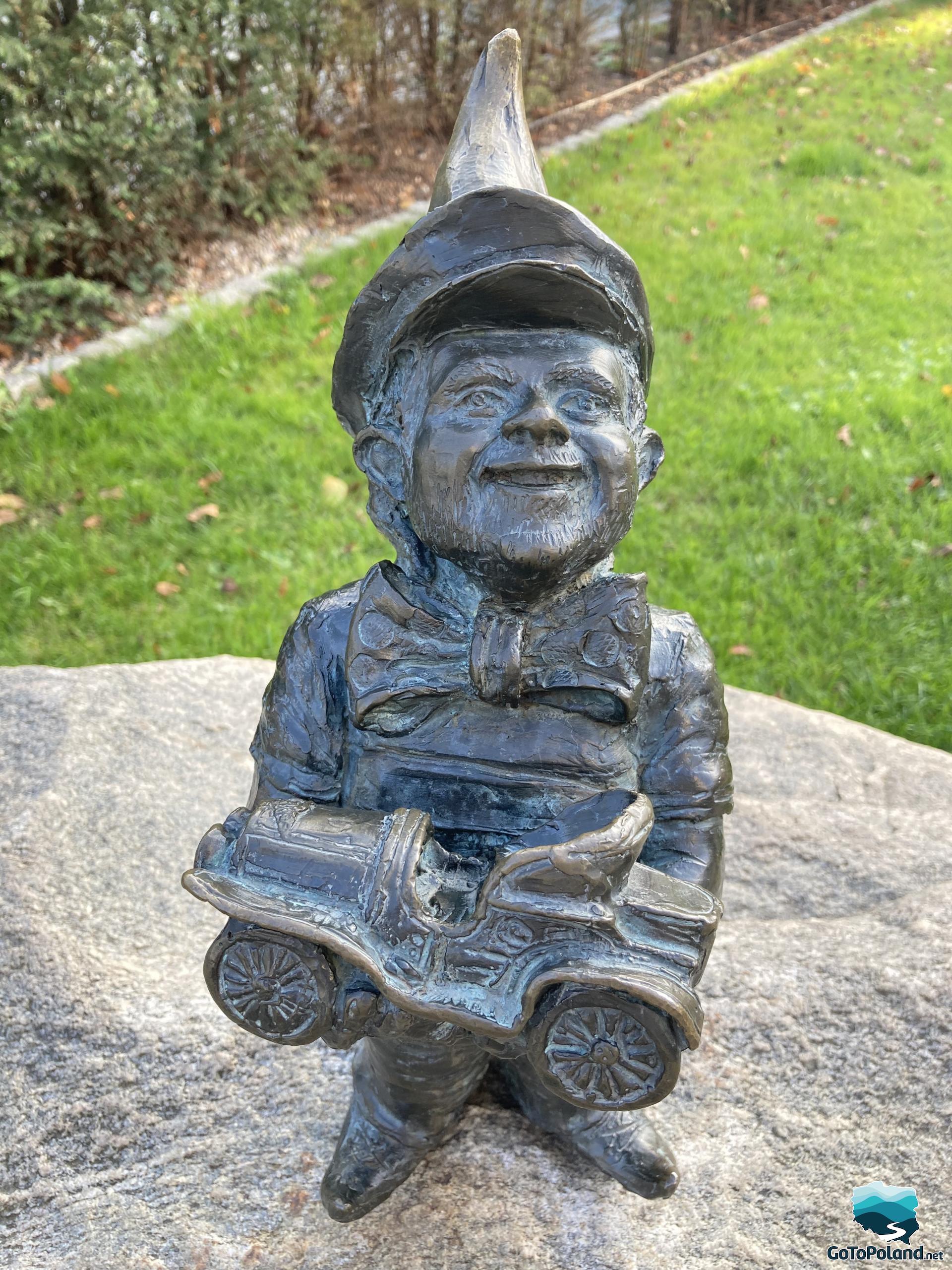 The sculpture shows a little gnome holding an old car in his hands